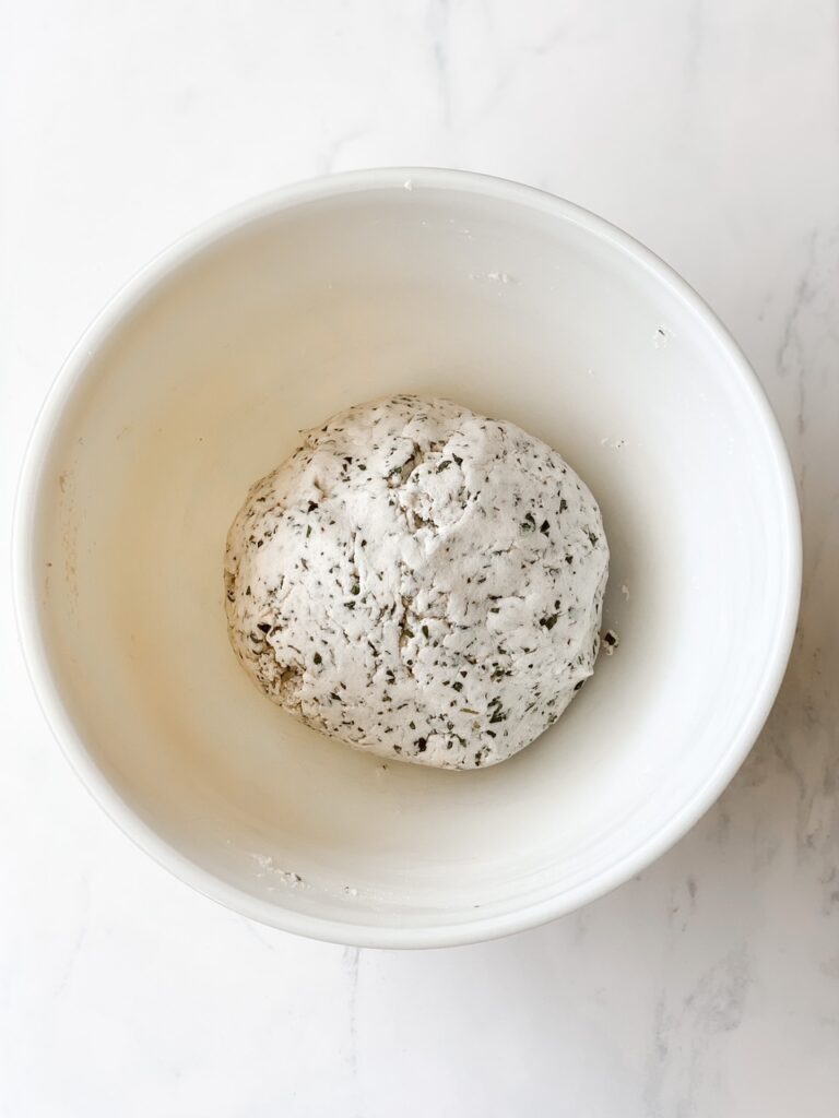overhead shot of gluten free sourdough cracker dough in a ball on a white marble backdrop