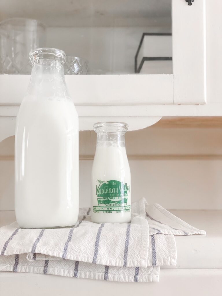 two jugs of raw milk on white china cabinet
