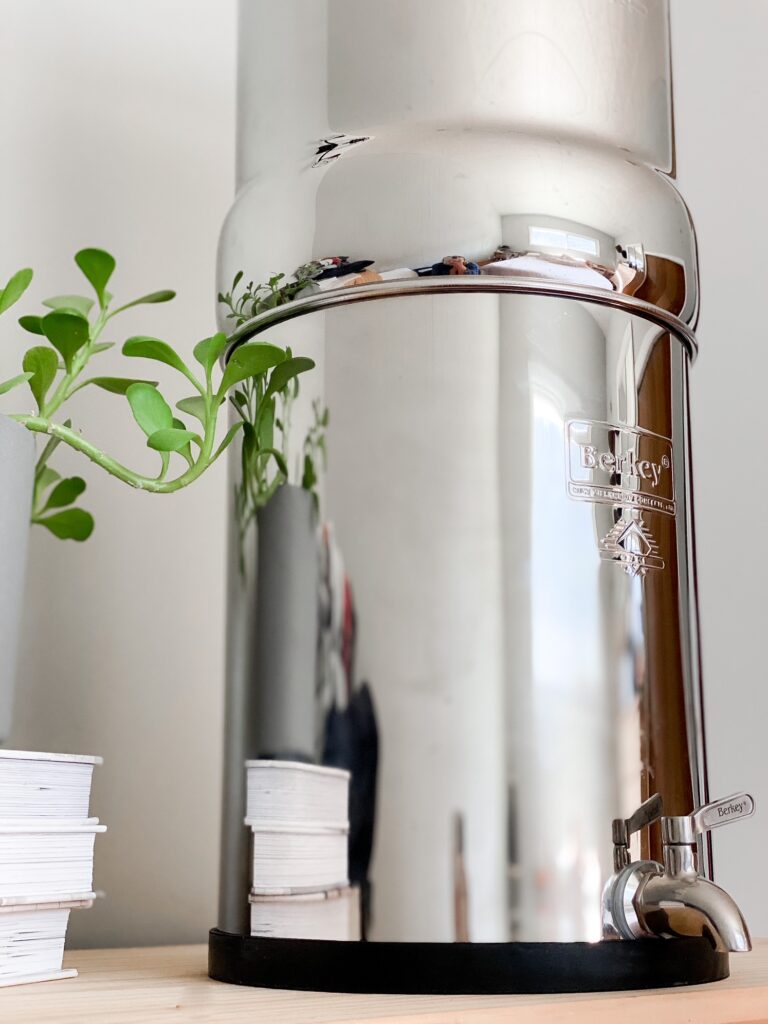 close up shot of berkey water filter with books and plant in background