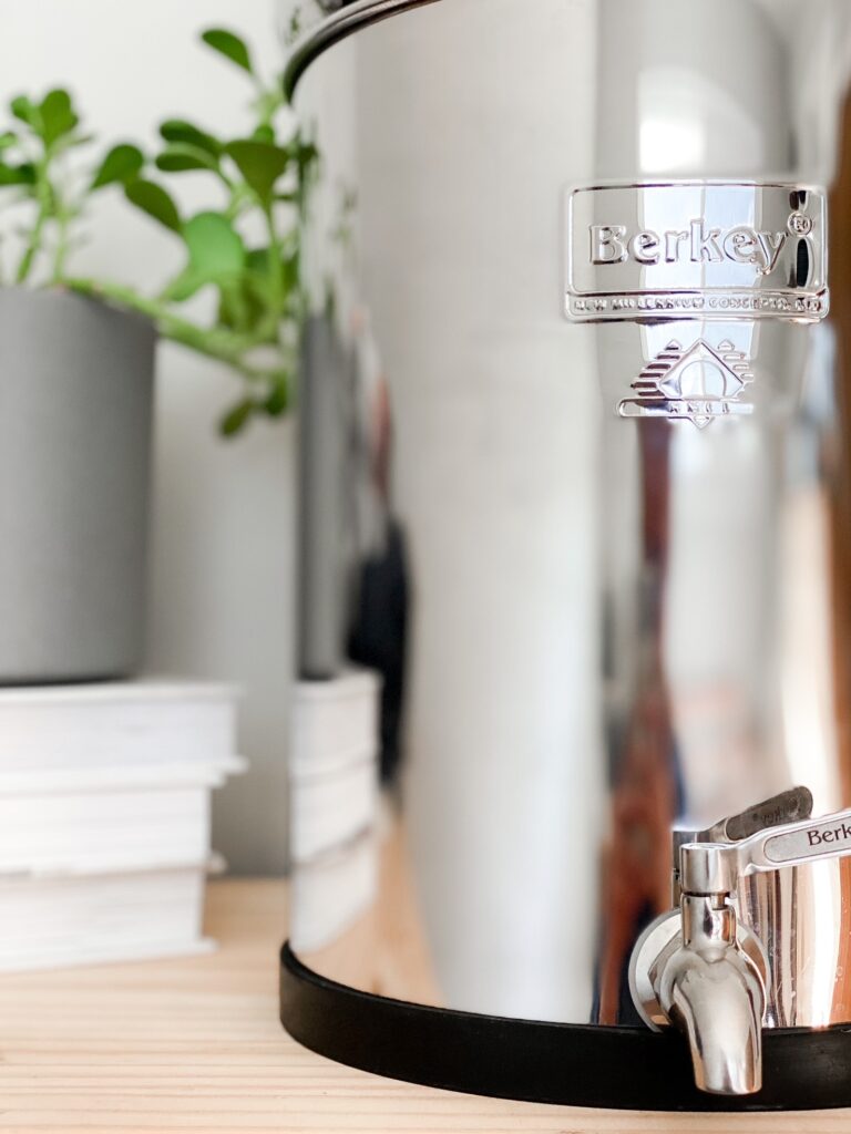 close up front shot of berkey water filter with potted plant and books in background