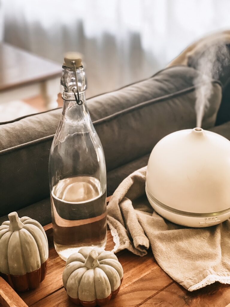 white diffuser with essential oils on a wood tray with bottle of water