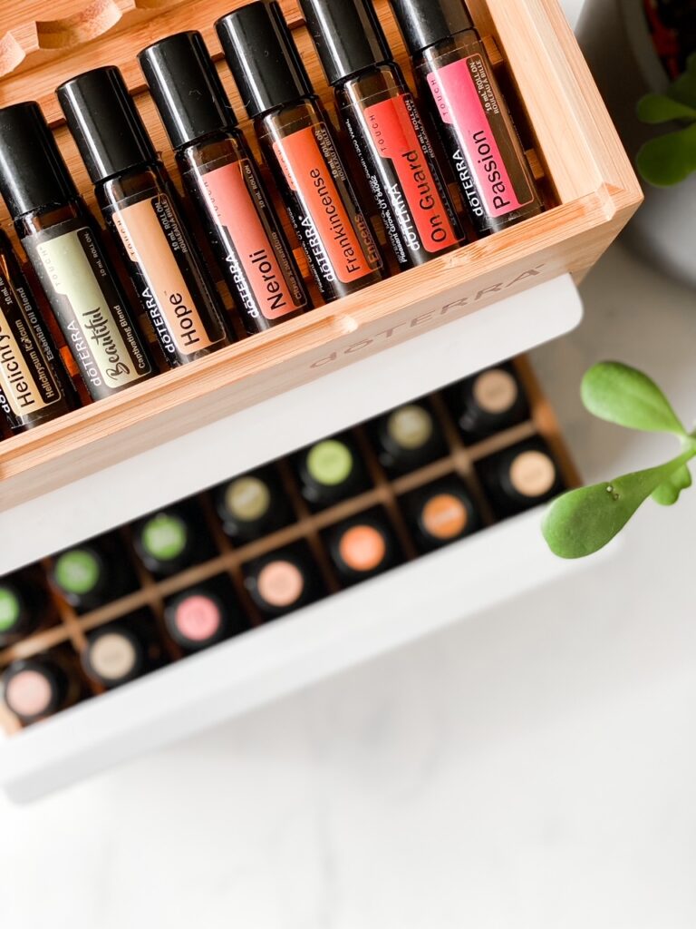 close up shot of doterra roller bottles and essential oils with plant on white backdrop