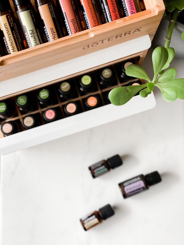 close up shot of drawer full of essential oils with white backdrop and jade plant