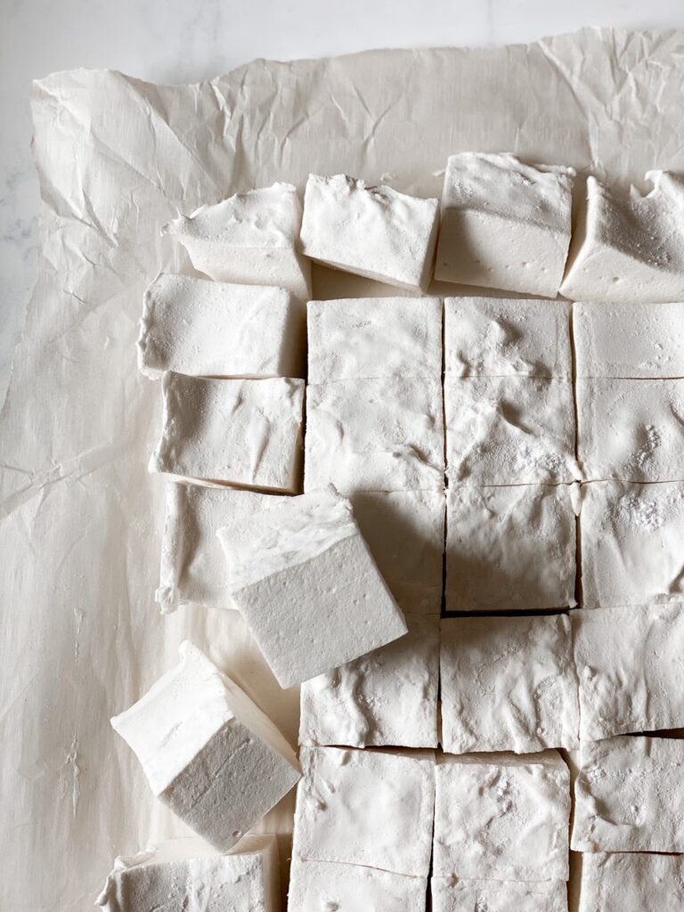 sliced homemade marshmallows on a marble backdrop with parchment paper