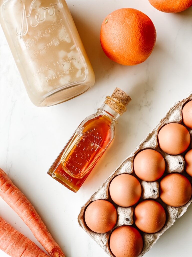 white backdrop with carrots honey eggs organes and bone broth