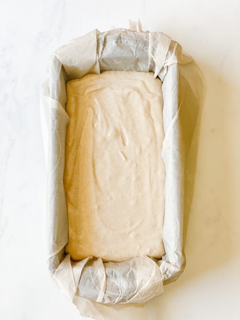 batter for gluten free bread poured into a parchment lined loaf pan