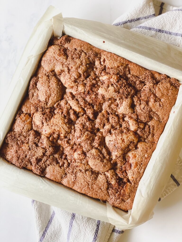 parchment lined pan with freshly baked coffee cake on a white and blue striped dish towel